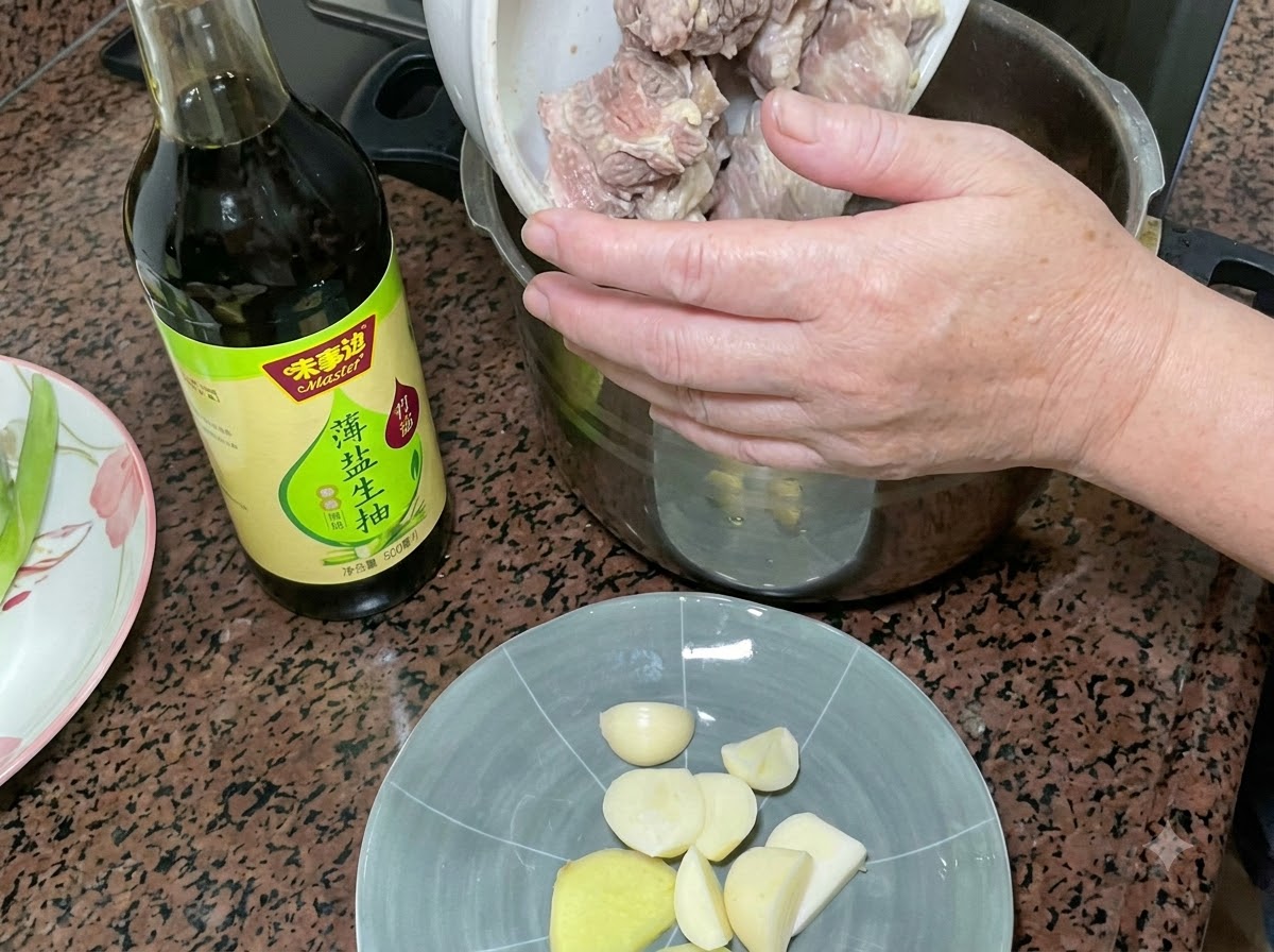 Costillas de cerdo escaldadas siendo vertidas en una olla a presión junto a una botella de salsa de soja clara y un plato de ajo y jengibre.