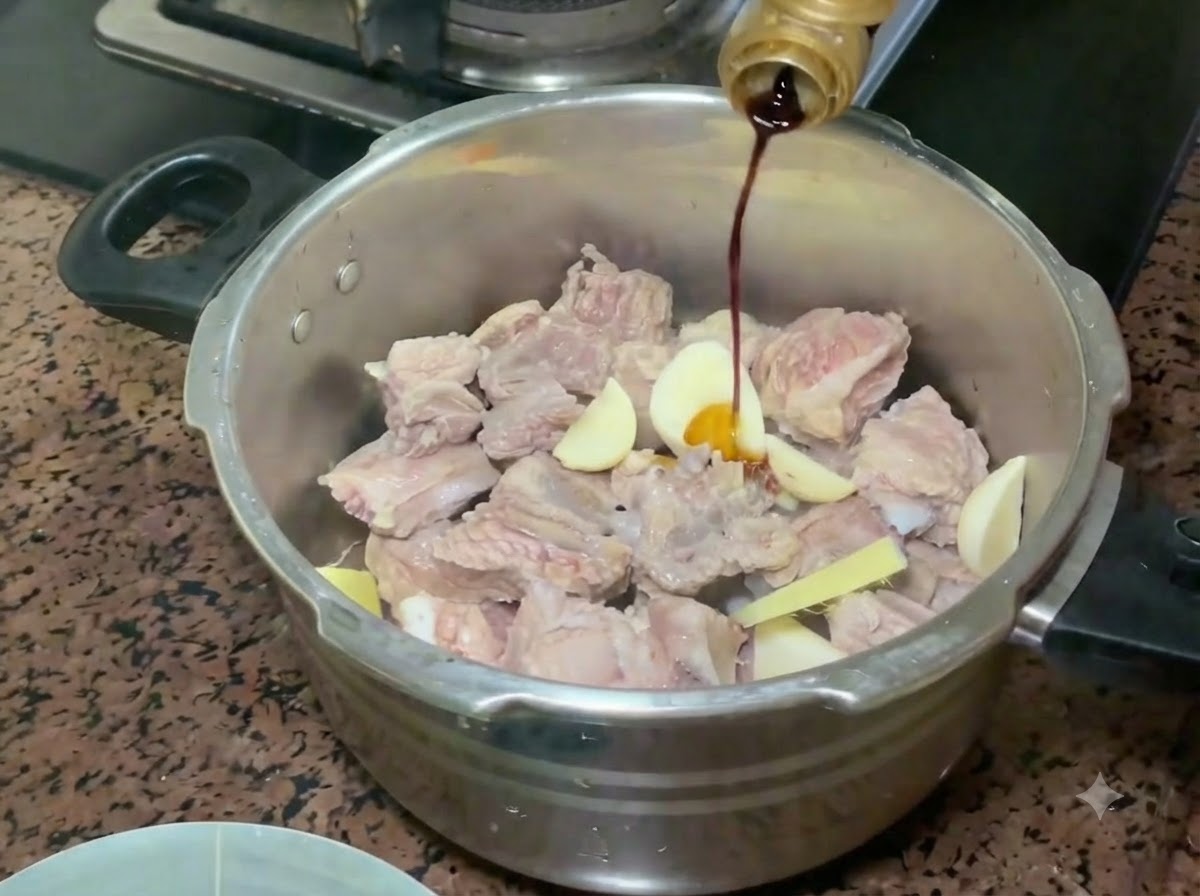Salsa de soja clara siendo vertida desde una botella sobre las costillas de cerdo y los aromáticos en la olla a presión.