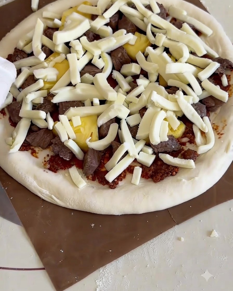 Una pizza cruda montada sobre una pala de madera deslizándose dentro de un pequeño horno de sobremesa con piedra de hornear.