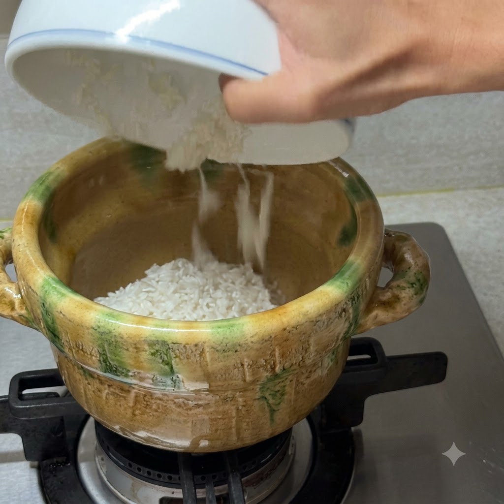 Caldo de almejas limpio siendo vertido desde un bol blanco en una cazuela de cerámica que contiene arroz blanco en una estufa de gas.