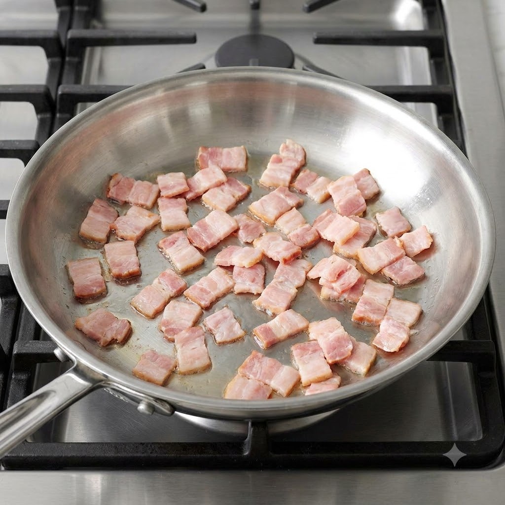 Trozos de tocino picado chisporroteando y dorándose en una sartén caliente de acero inoxidable.