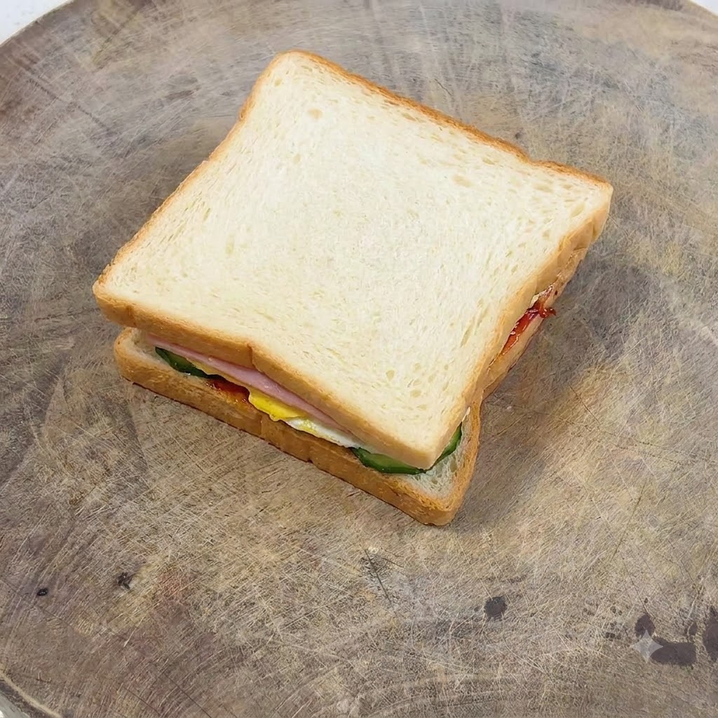 Un tenedor esparciendo mayonesa suavemente sobre una rebanada dorada de pan tostado.