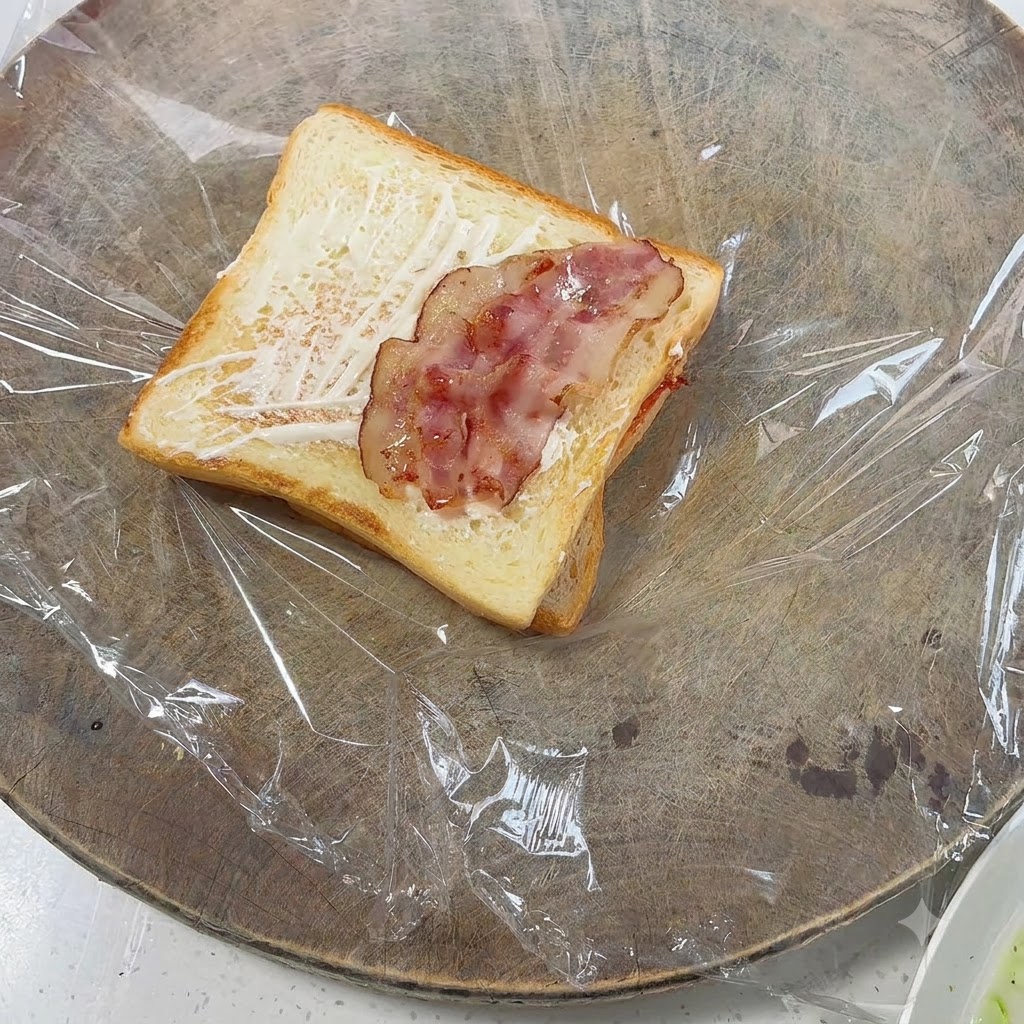 Trozos de tocino cocido colocados encima del pan tostado.