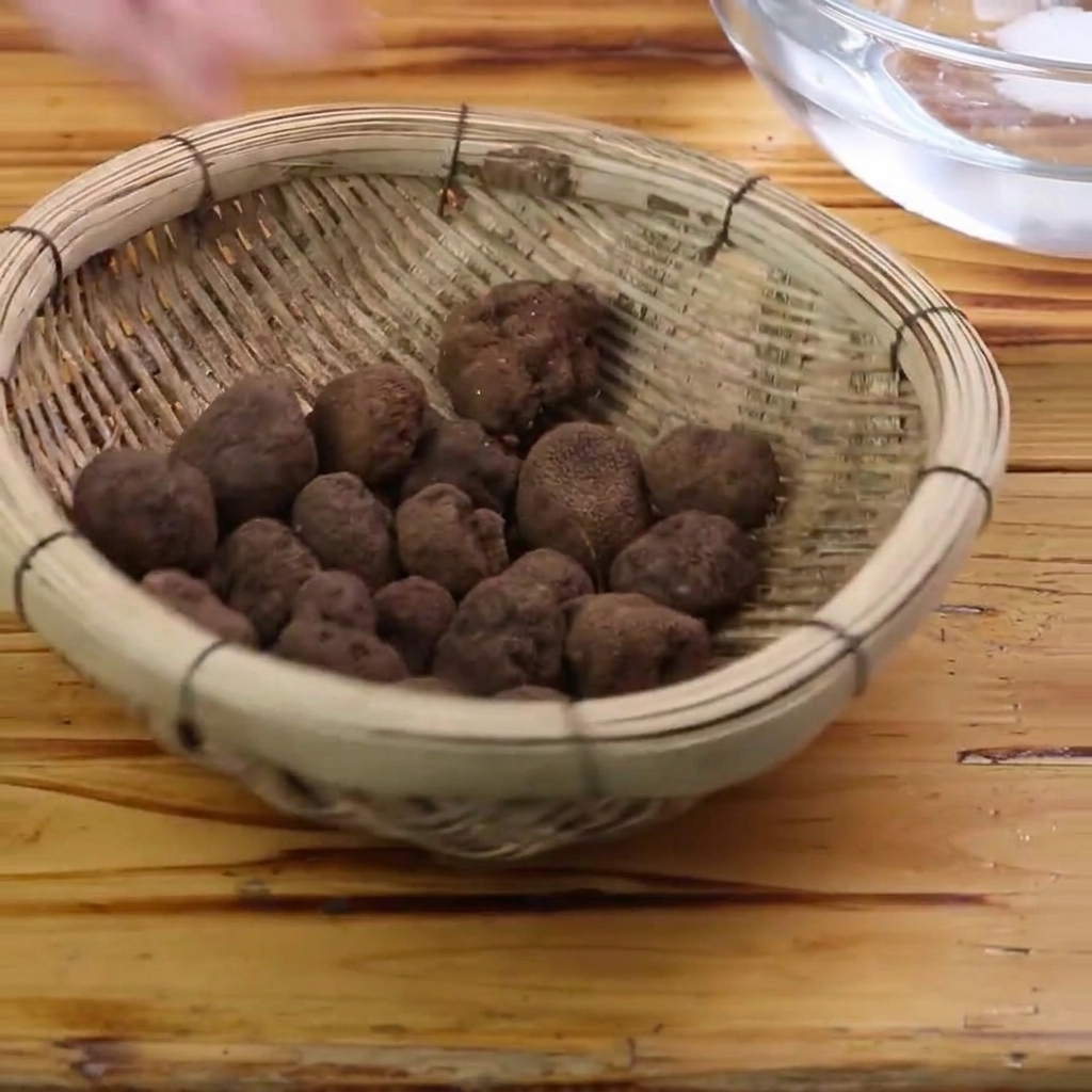 Trufas negras frescas siendo limpiadas con un cepillo dentro de un recipiente con agua.