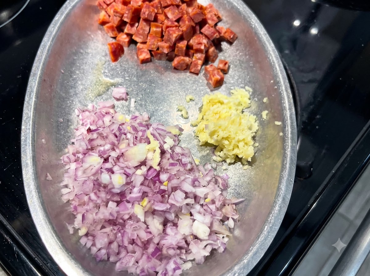 Un plato de metal que contiene montones de cebolla roja en dados, ajo picado y cubos de chorizo español.