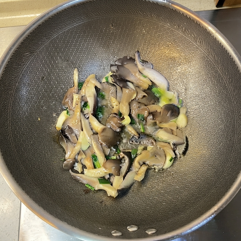 Champiñones ostra cocidos y aromáticos siendo mezclados dentro del wok.