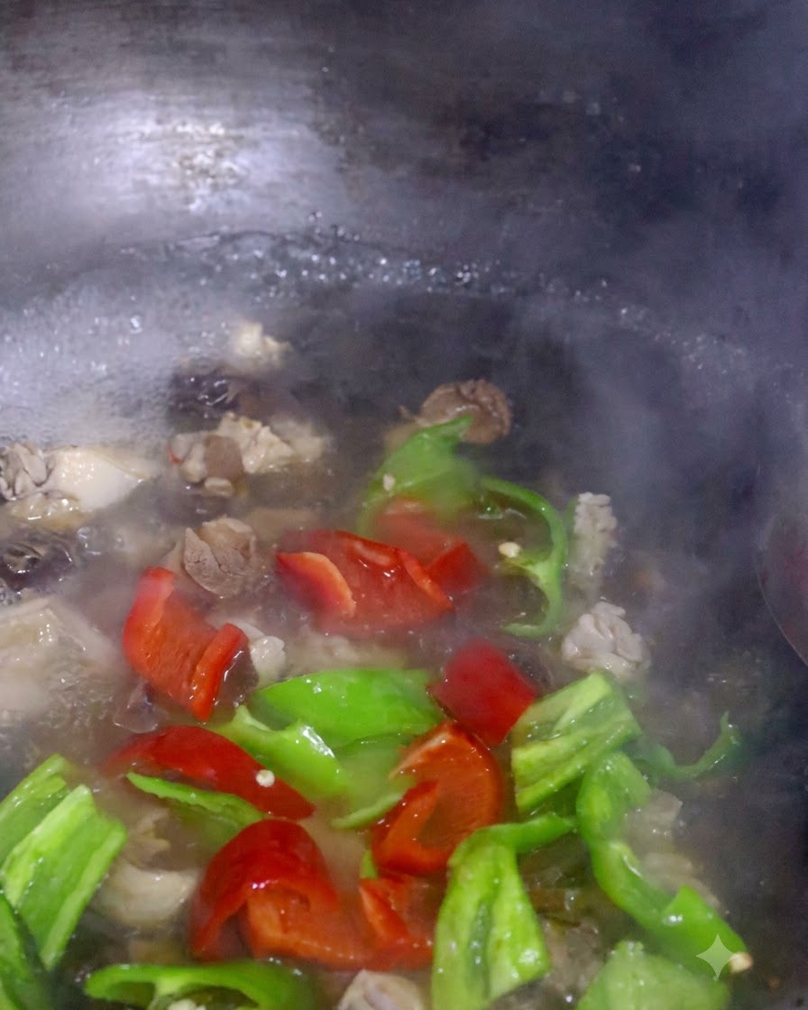 Tiras de pimiento rojo y verde y pak choi hirviendo junto con los hongos en una olla.