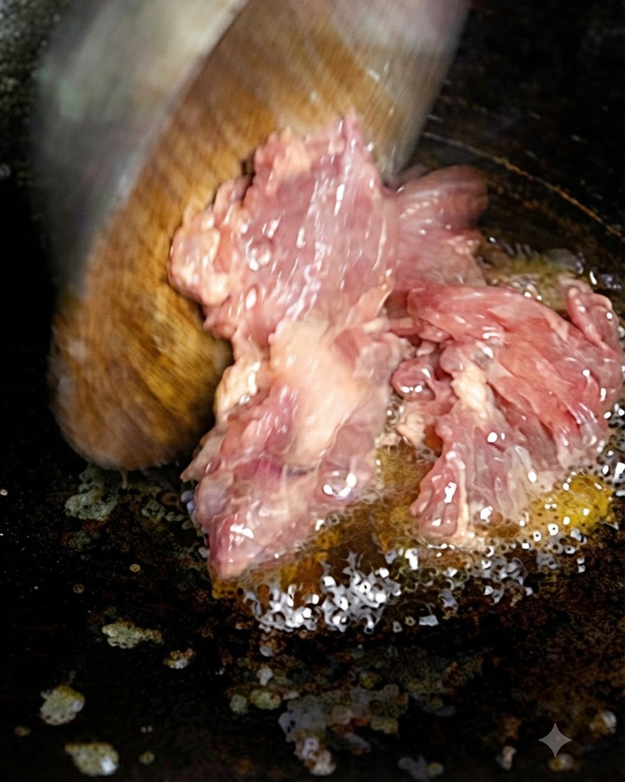 Carne picada siendo añadida al aceite caliente en una sartén usando una espátula de madera.