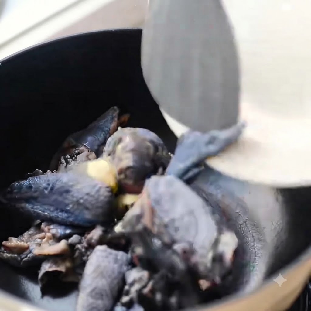 Trozos de pollo de piel negra salteándose en una olla negra con jengibre.