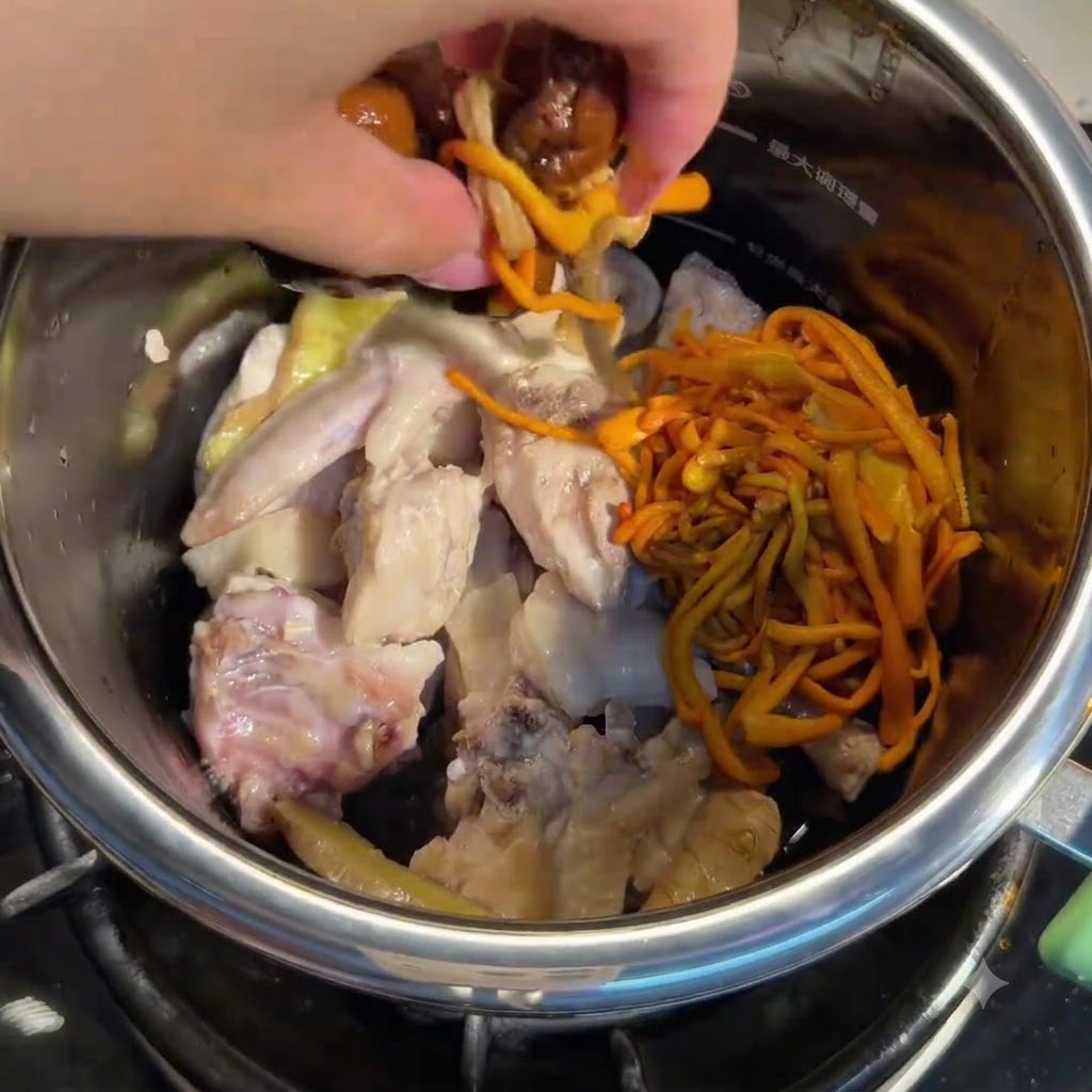 Mano añadiendo hongos remojados y flores de cordyceps en la olla con pollo.
