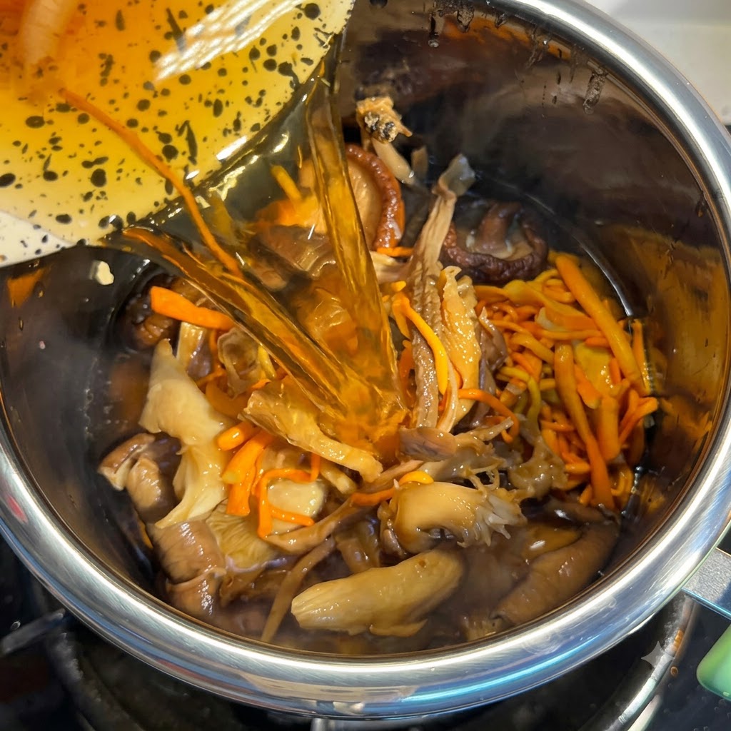 Agua de remojo de hongos siendo vertida en la olla llena de ingredientes.