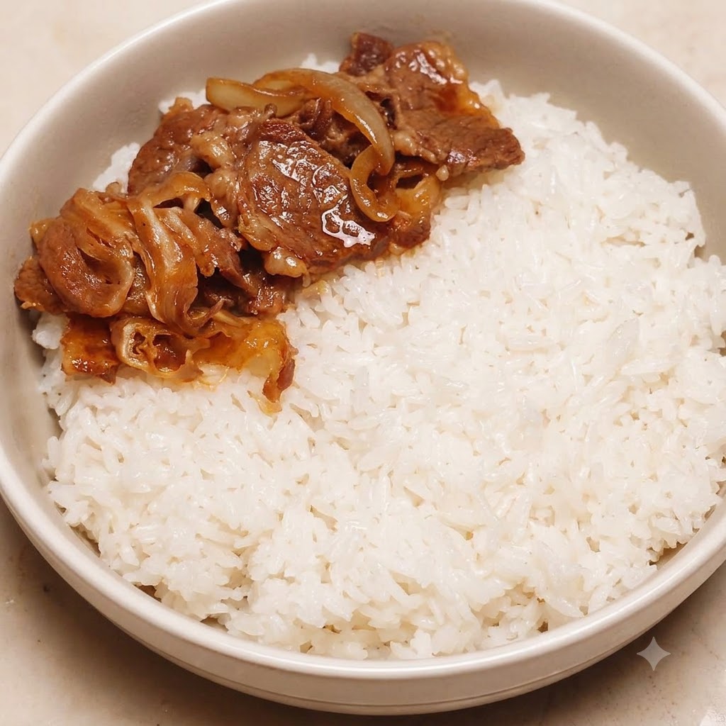 Ternera y cebollas cocinadas colocadas ordenadamente en un lado de un bol lleno de arroz blanco.