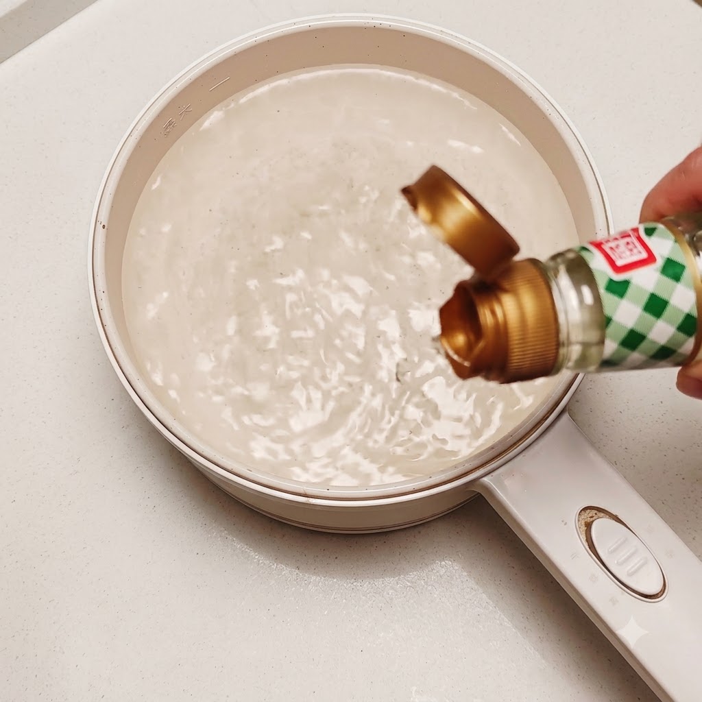Un huevo crudo comestible siendo introducido en una olla con agua caliente en remolino con un poco de vinagre de arroz.