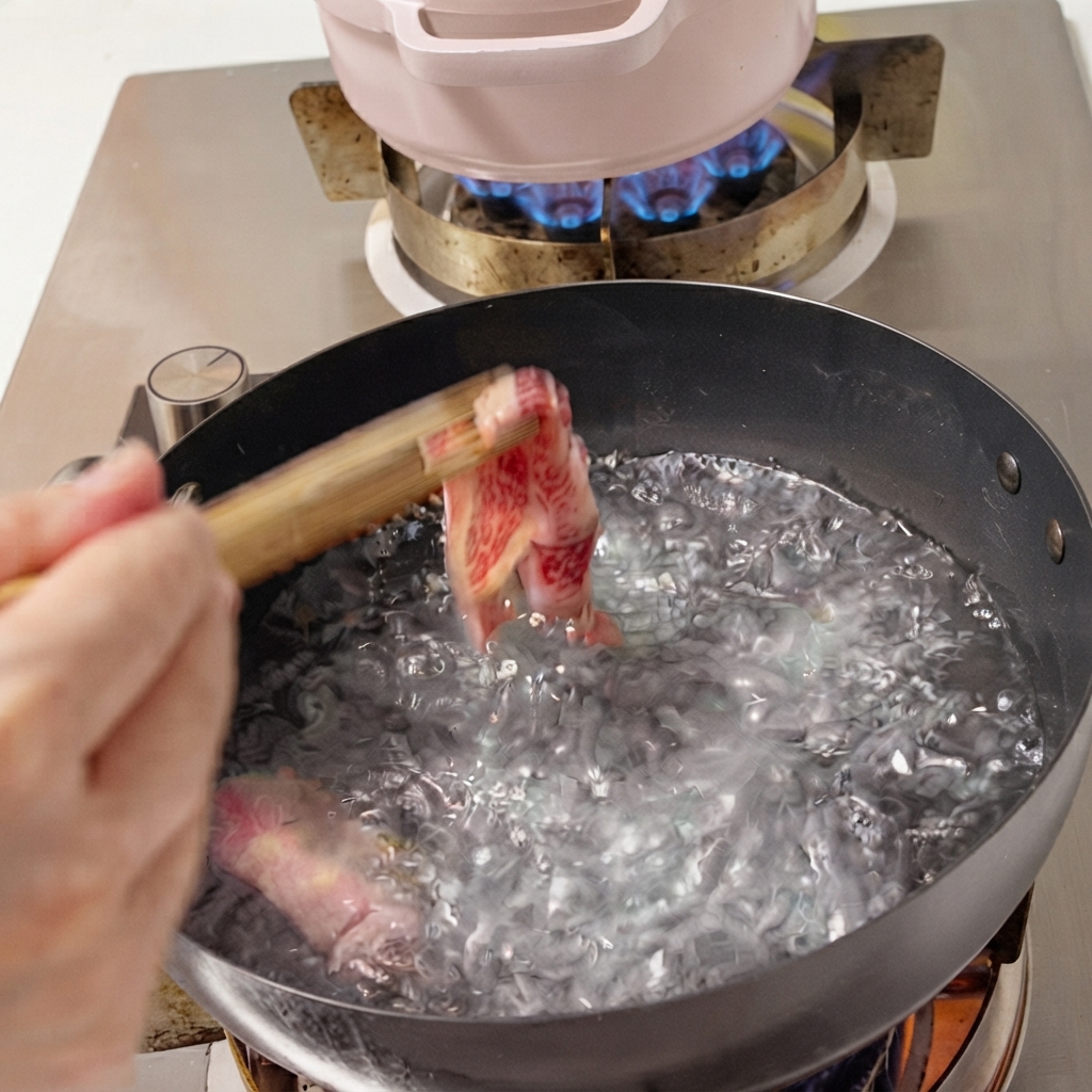 Lonchas de ternera fresca siendo introducidas en una olla con agua hirviendo con palillos.