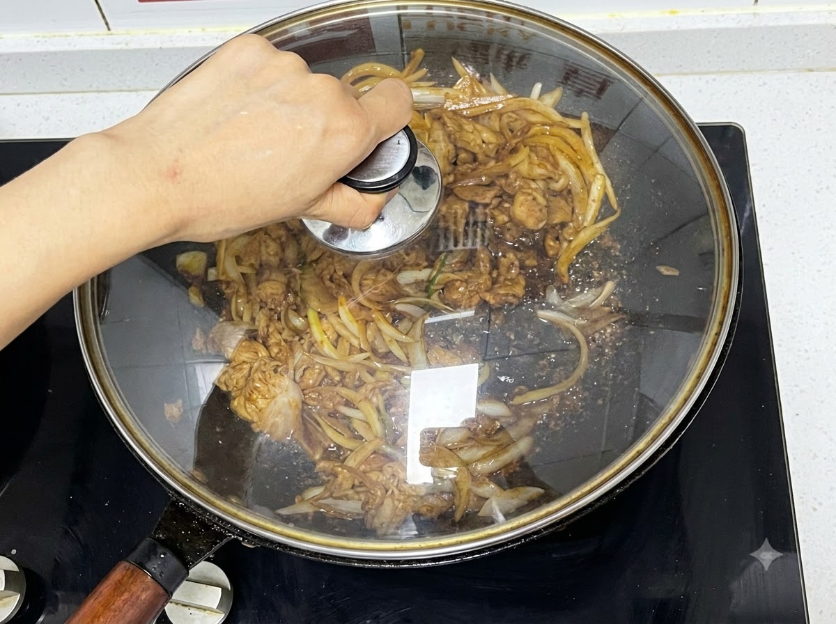 Una tapa de vidrio colocada sobre un wok que contiene carne y cebollas cocinándose a fuego lento.
