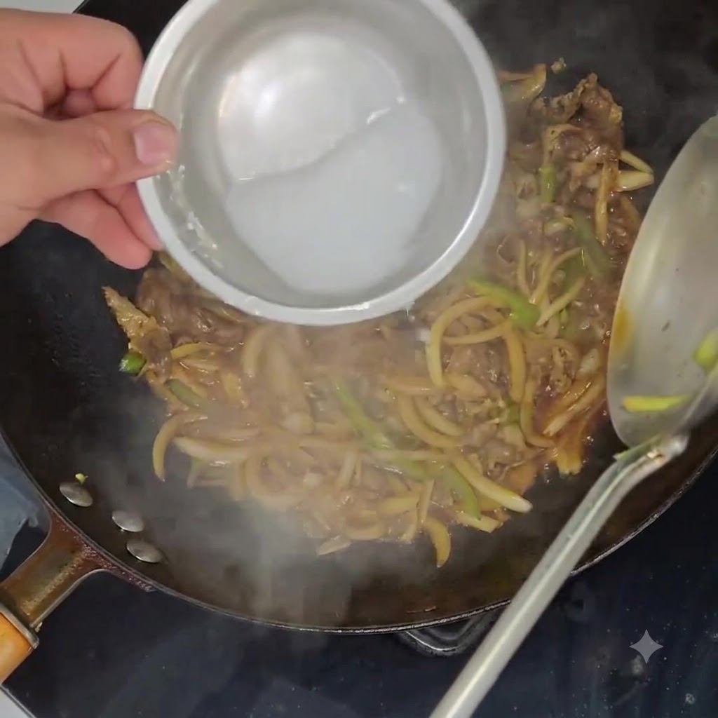 Una mezcla líquida de almidón de patata vertida desde un pequeño bol hacia el interior de un wok lleno de carne y verduras a fuego lento.