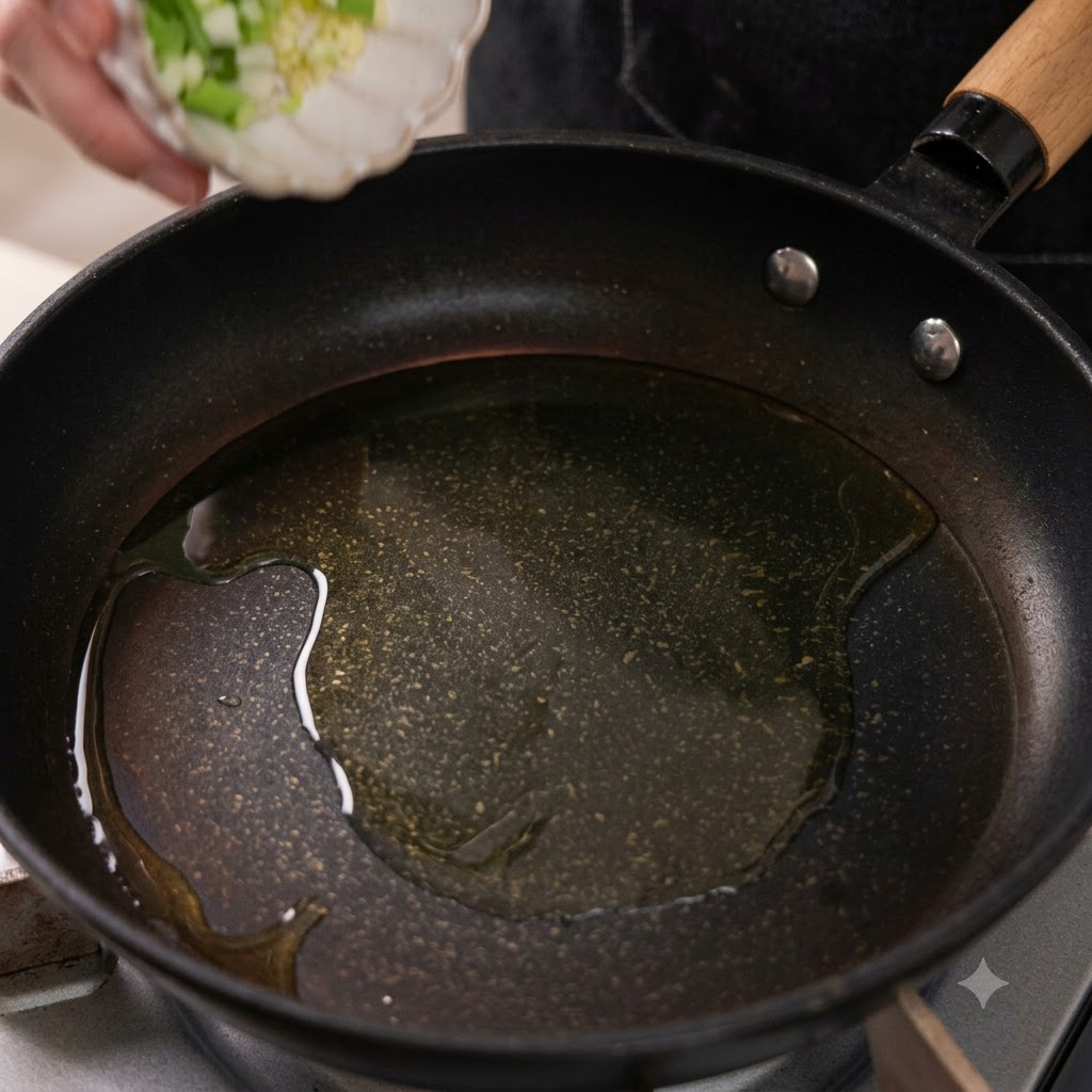 Ajo picado y la parte blanca de la cebolleta cayendo en una sartén con aceite caliente.