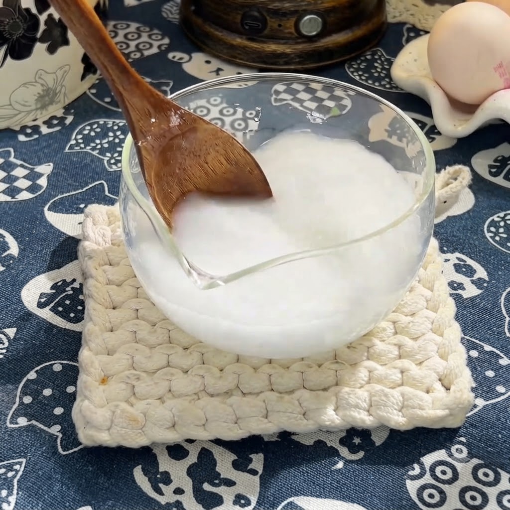 Una cuchara de madera revolviendo salsa de soja, salsa de ostras y miel en la mezcla de maicena.