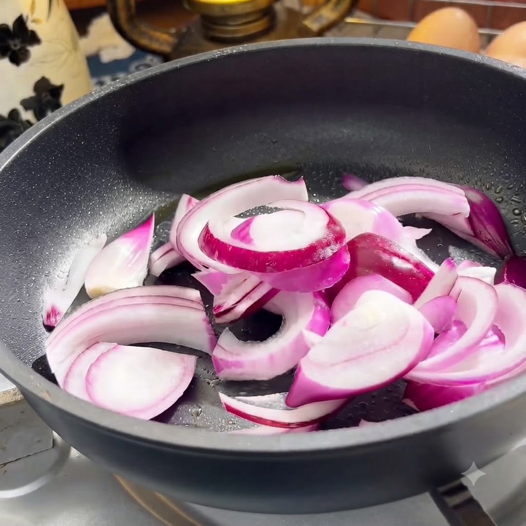 Cebolla morada y rodajas de ternera cocinándose en una sartén.