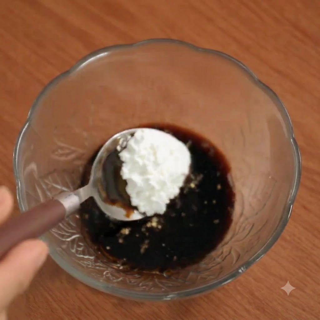 Una cucharada de maicena siendo añadida al bol de la salsa.