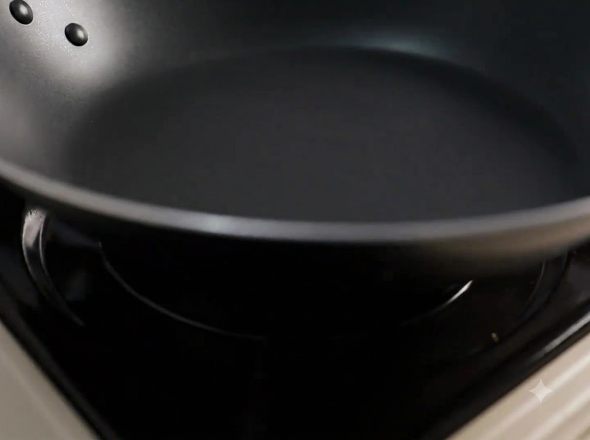 Aceite de cocina siendo vertido en una sartén negra caliente.