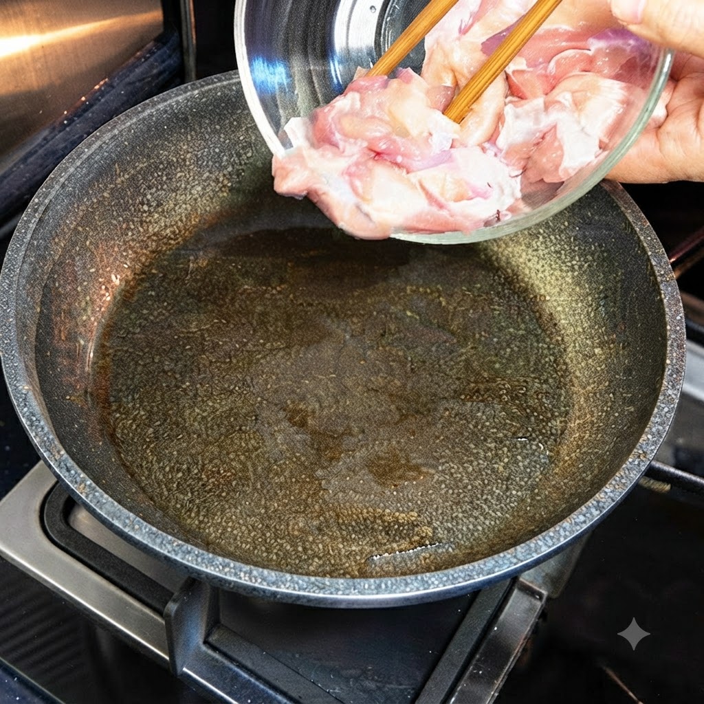 Trozos de pollo crudo siendo vertidos desde un tazón de vidrio en una sartén caliente con aceite.