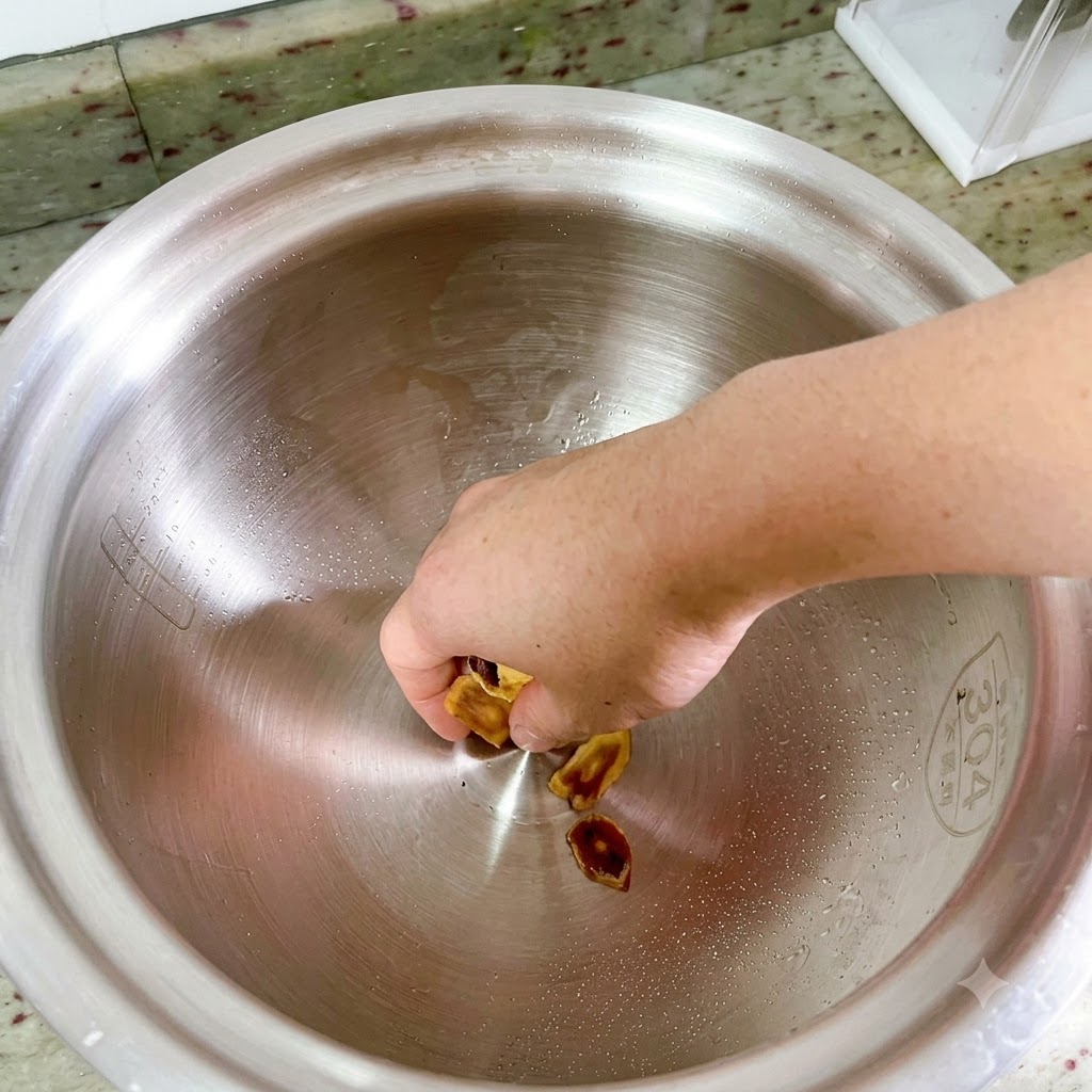 Una mano colocando rodajas de ginseng coreano en el fondo de una olla de metal grande y vacía.