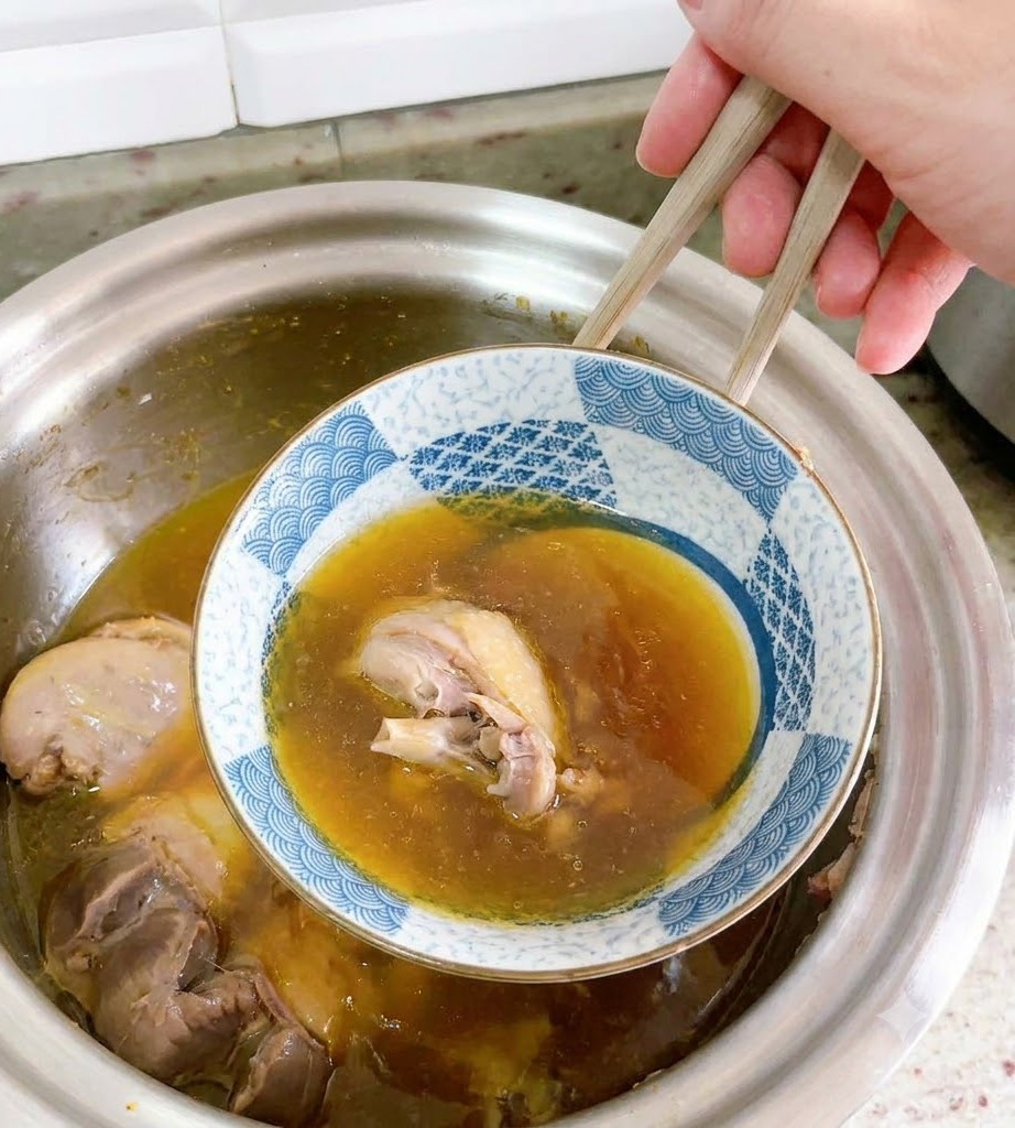 Un tazón de cerámica invertido siendo levantado cuidadosamente de la sopa de pato con palillos.