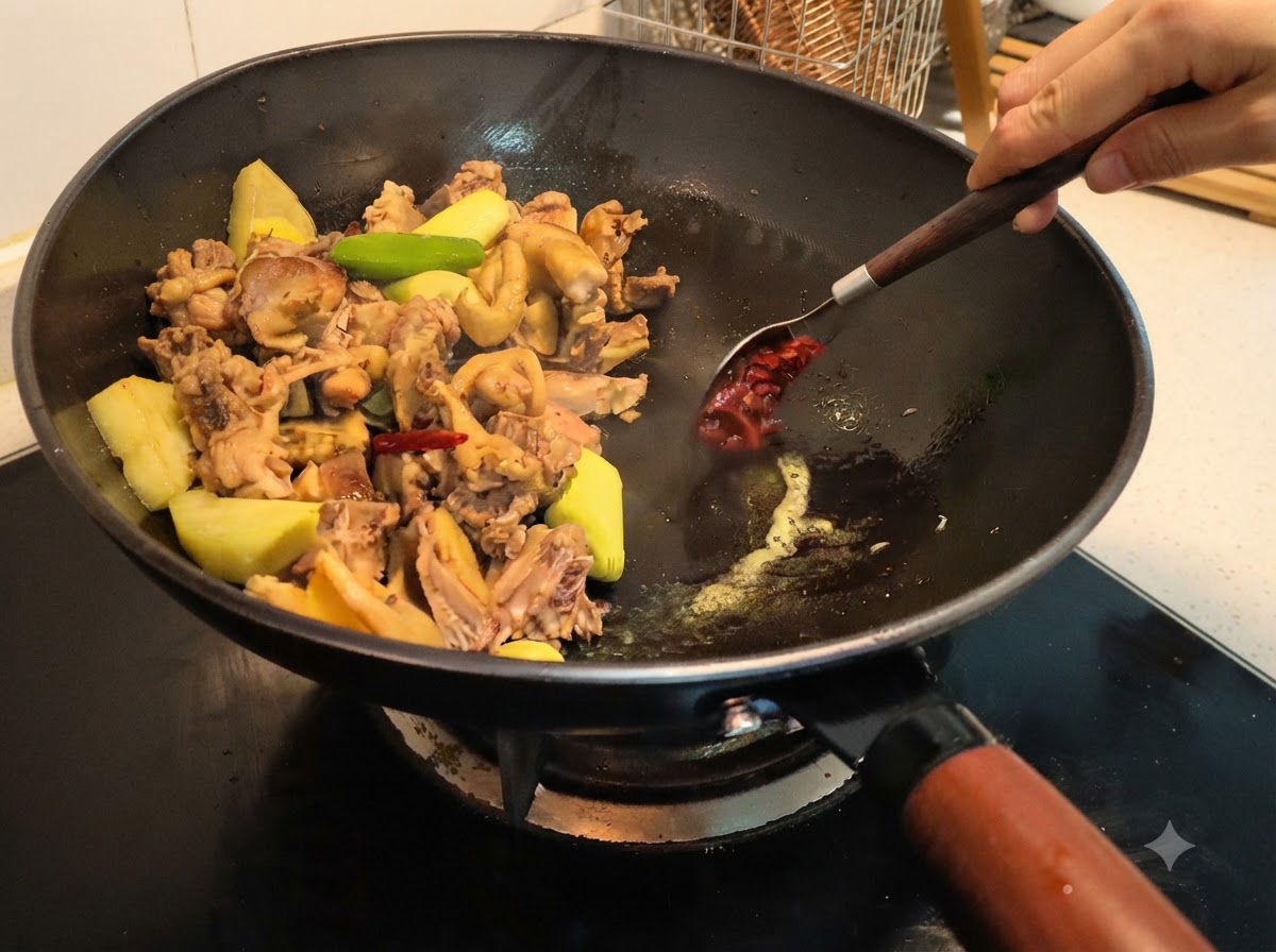 Pasta de habas siendo cucharada en el wok y mezclada con los ingredientes usando una cuchara.