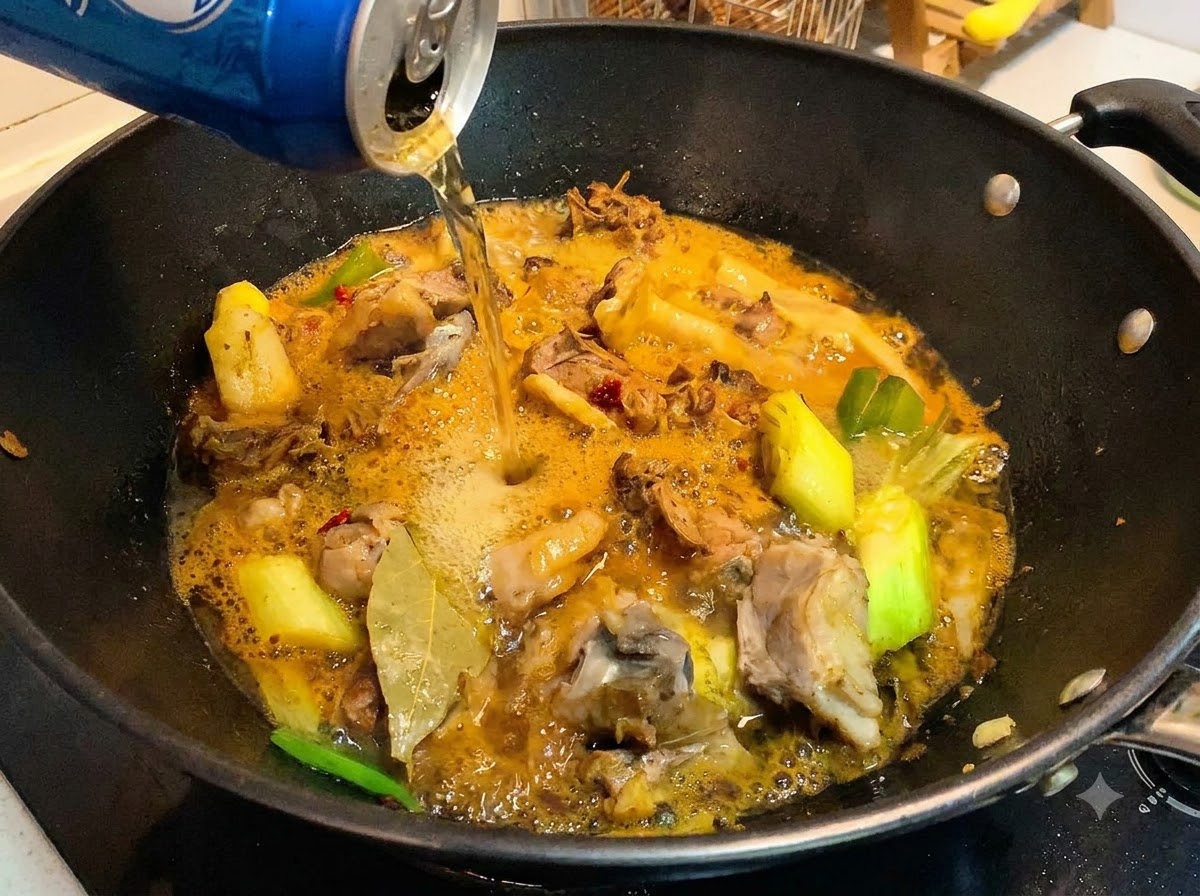 Una lata de cerveza siendo vertida en un wok que contiene trozos de pato cocinados y una salsa rica y burbujeante.