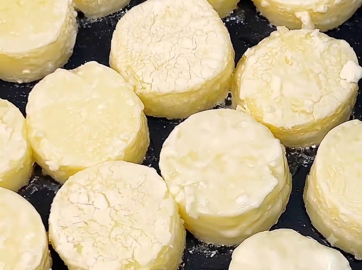 Rodajas de tofu japonés friéndose en aceite caliente en una sartén negra hasta que sus superficies se doren.