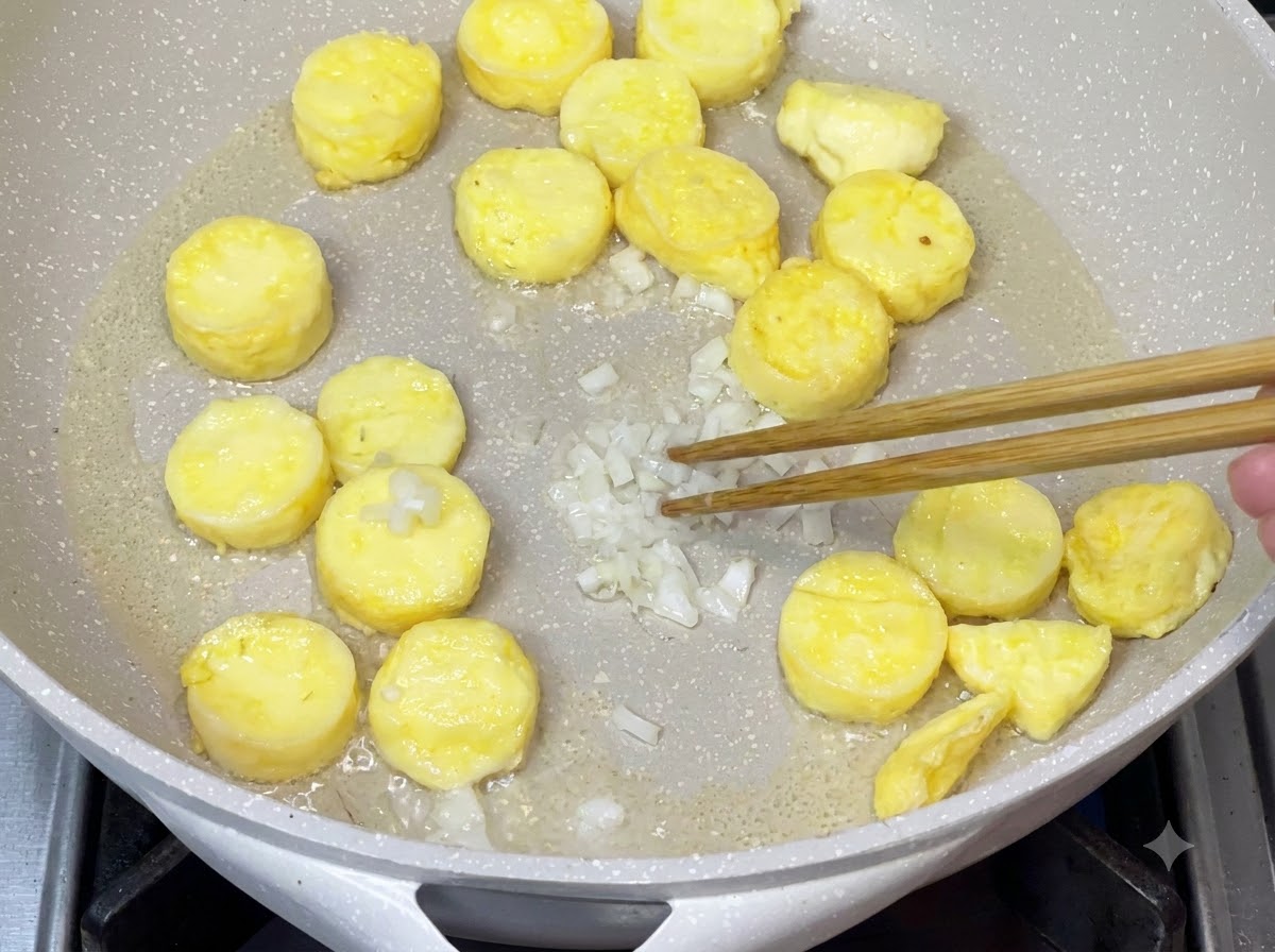 Cebolleta picada siendo salteada en la sartén después de retirar el exceso de aceite para potenciar el aroma.
