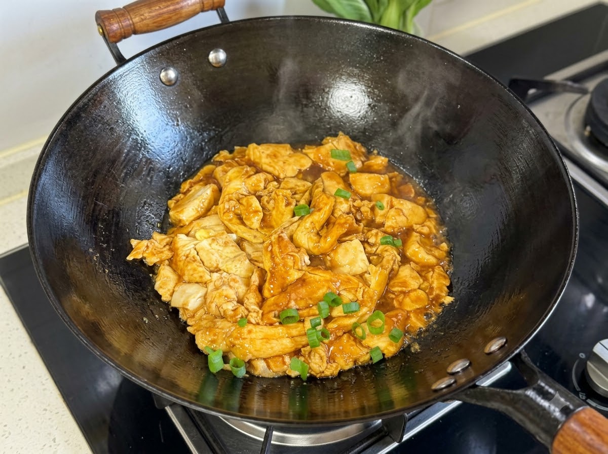 Cebollas verdes picadas esparcidas encima de la mezcla cocida de tofu y huevo en un wok negro.