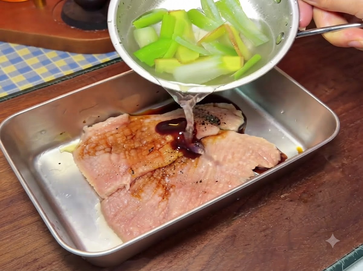 Un pequeño cuenco vertiendo líquido sobre chuletas de cerdo dentro de un recipiente de metal más grande.