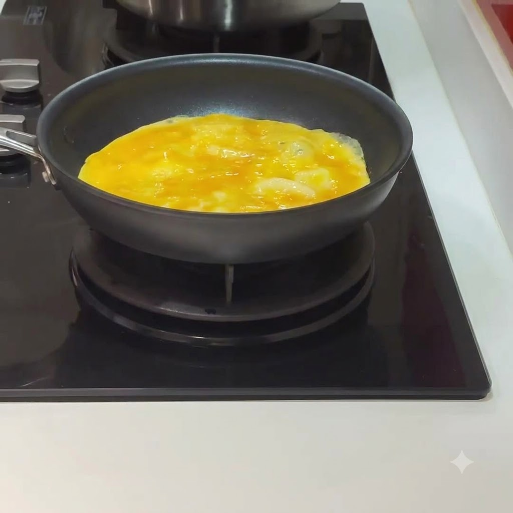 Un huevo cocinándose y comenzando a cuajar dentro de una sartén negra en una estufa.