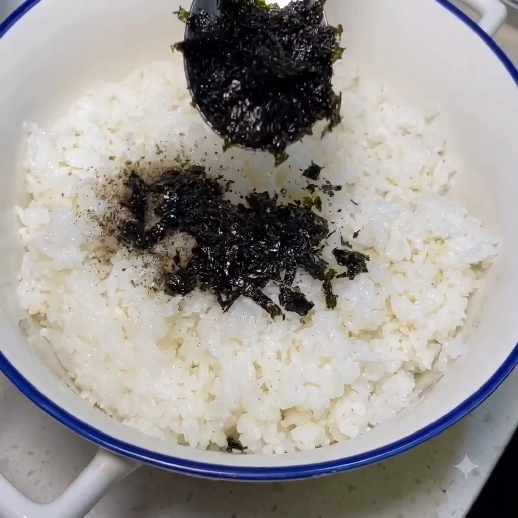 Polvo de algas siendo espolvoreado sobre arroz blanco cocido.