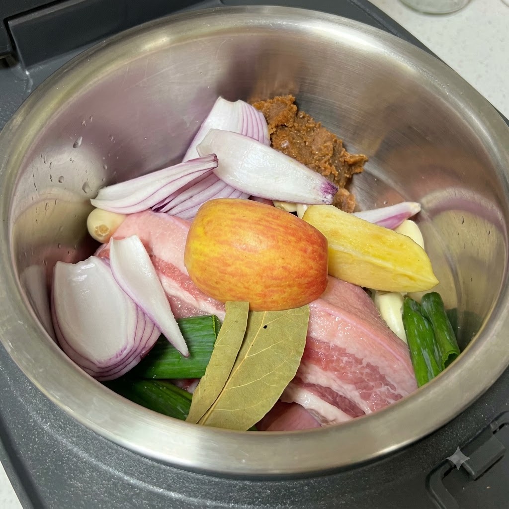 Sal siendo molida sobre la panceta de cerdo cruda, los aromáticos y la pasta de soya dentro de la olla de cocción.