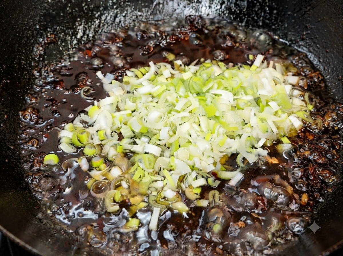 Cebollines verdes recién picados siendo mezclados en la salsa frita caliente terminada fuera del fuego.
