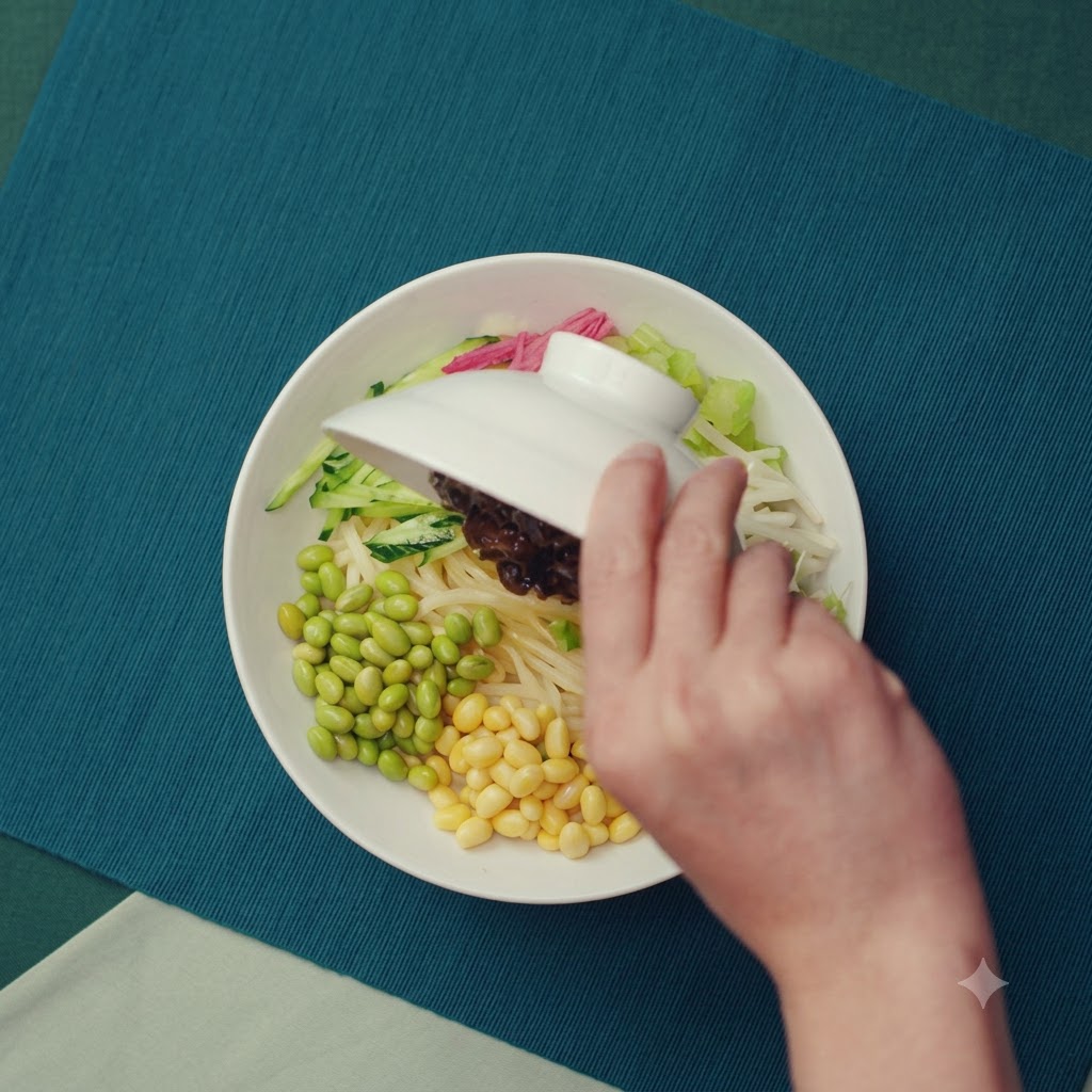 Salsa espesa y marrón de cerdo picado siendo vertida desde un bol sobre una cama de fideos y aderezos de verduras.