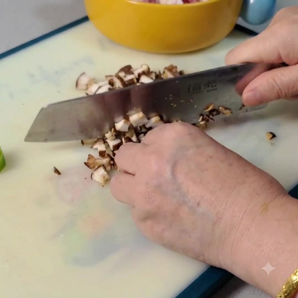 Setas shiitake crudas siendo rebanadas y picadas en trozos pequenos sobre una tabla de cortar.