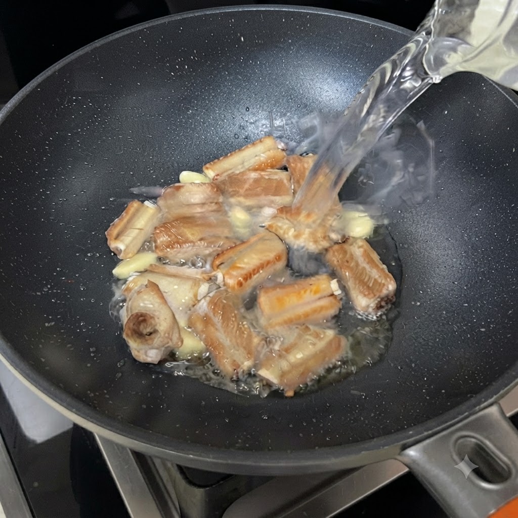 Agua fluyendo desde un tazón hacia la sartén chisporroteante con costillas y ajo.