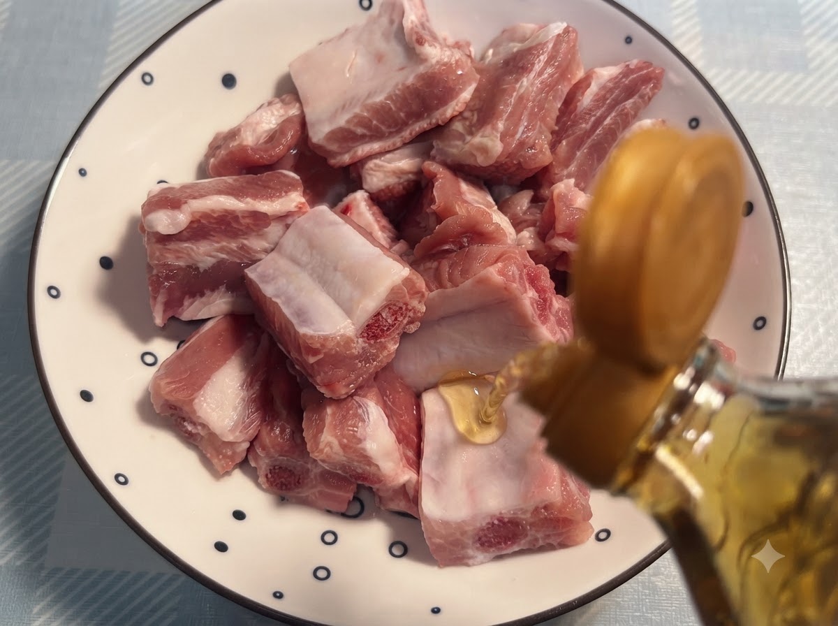 Vino para cocinar siendo vertido de una botella sobre costillas de cerdo crudas dispuestas en un plato con patrón.