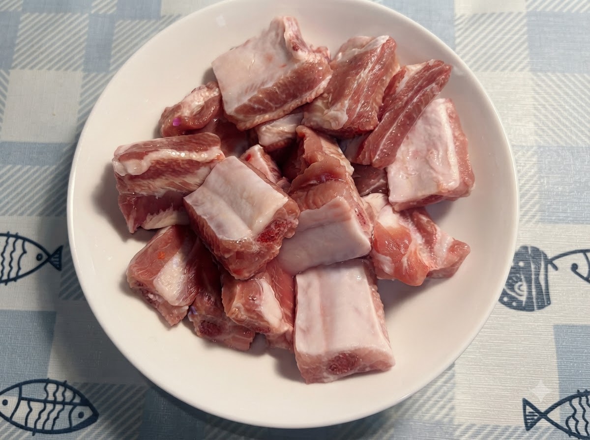 Una pequeña cuchara blanca añadiendo sal sobre las costillas de cerdo crudas en el plato.