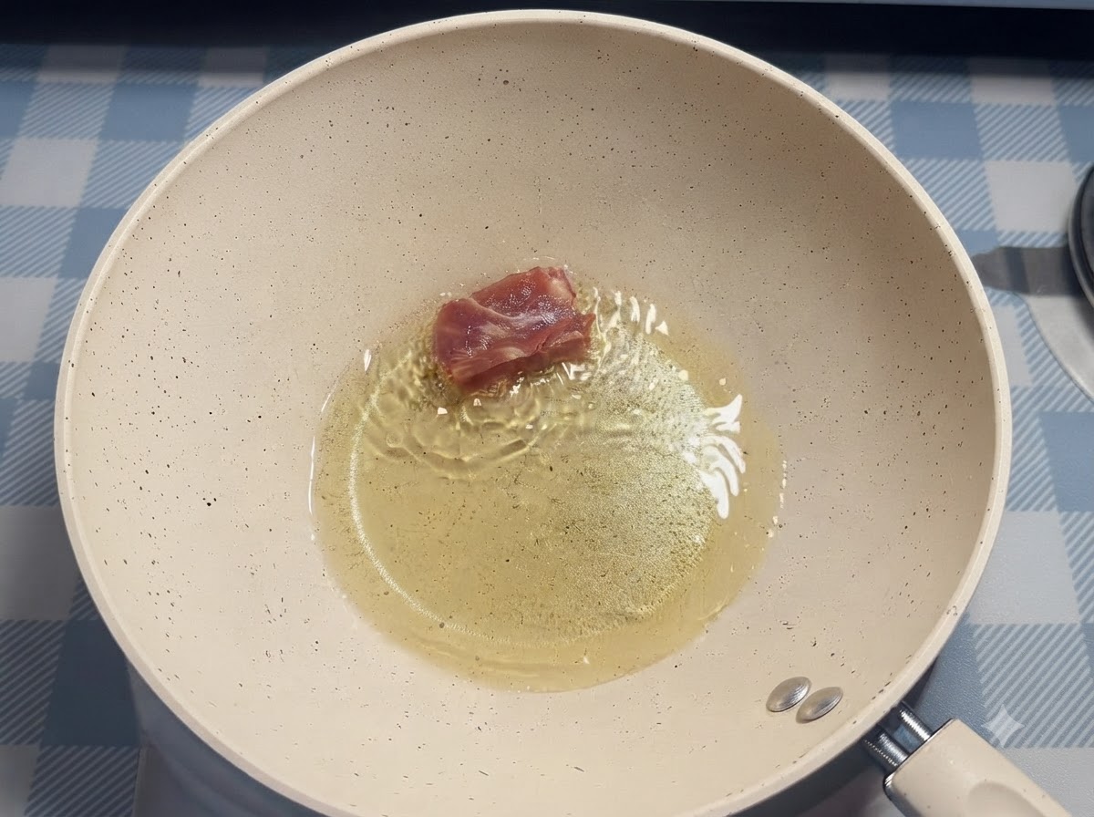 Una sola pieza de costilla de cerdo siendo colocada en aceite caliente dentro de una sartén blanca usando palillos.