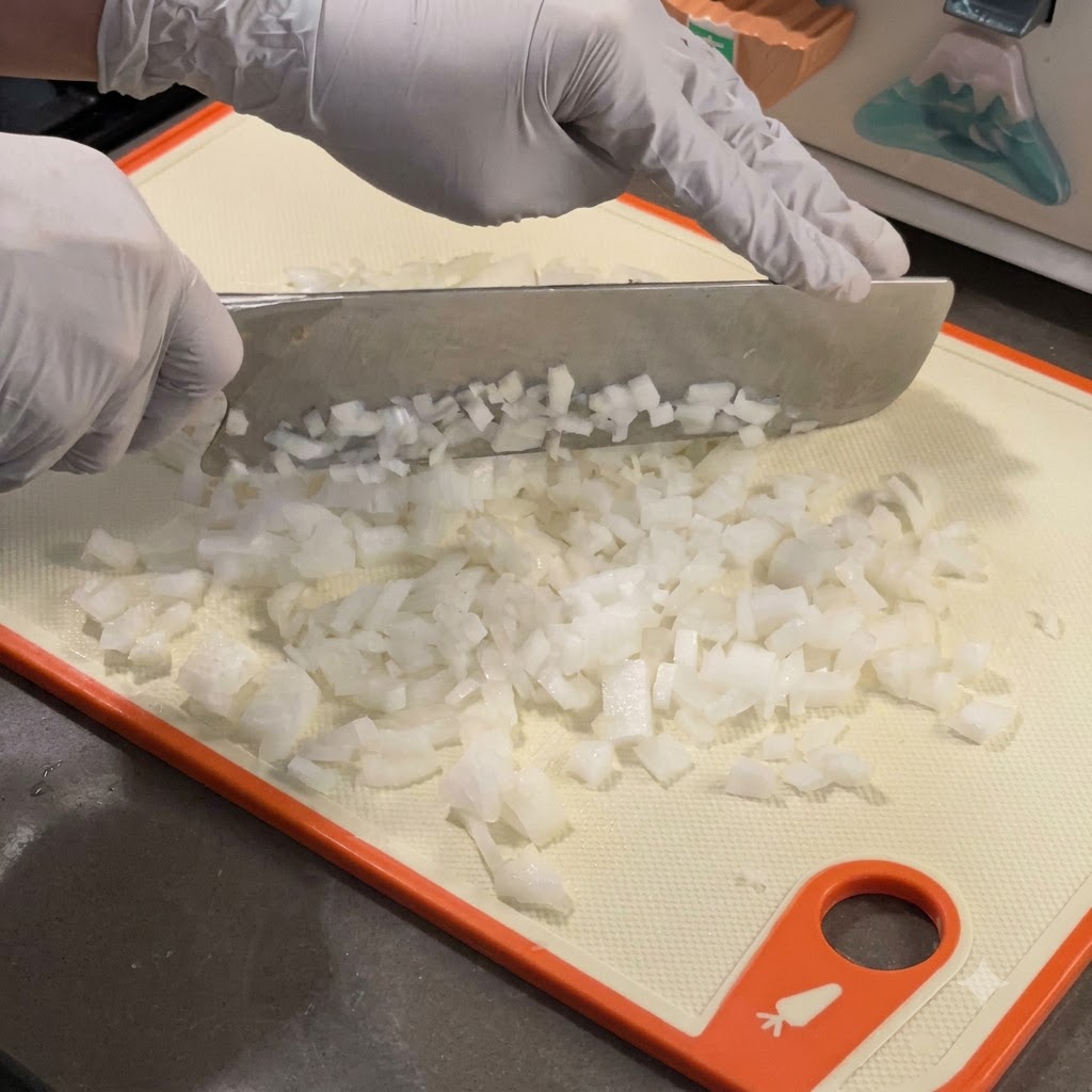 Cebollas blancas finamente picadas cocinándose en una sartén de hierro fundido caliente.
