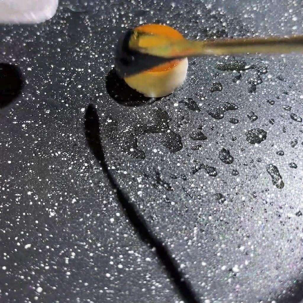 Líquido de huevo amarillo siendo exprimido en el centro de un pequeño aro de champiñón hueco dentro de una sartén caliente con motas.