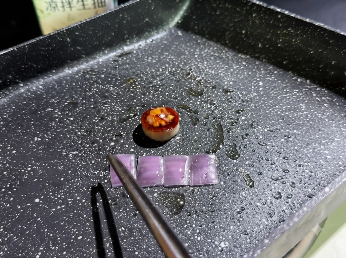 Cuatro rodajas rectangulares pequeñas de cebolla morada friéndose en una sartén aceitada junto al aro de champiñón relleno.