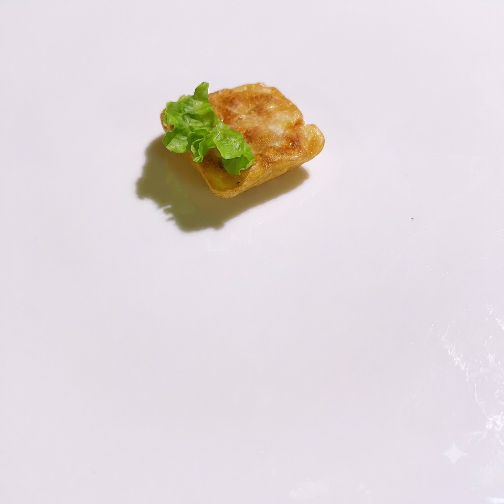 Trozos de lechuga verde fresca dispuestos alrededor de una base cuadrada cocinada en un plato blanco.