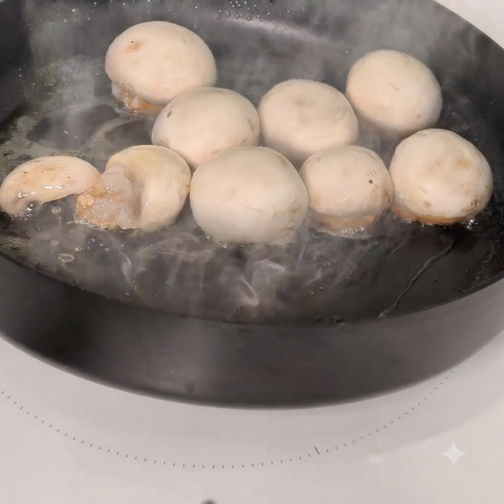 Tapas de champiñones rellenos de camarón cocinándose en una sartén caliente.