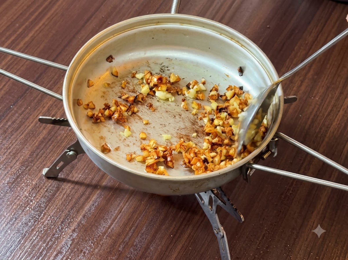 Ajo picado siendo revuelto y dorado en mantequilla dentro de una sartén.